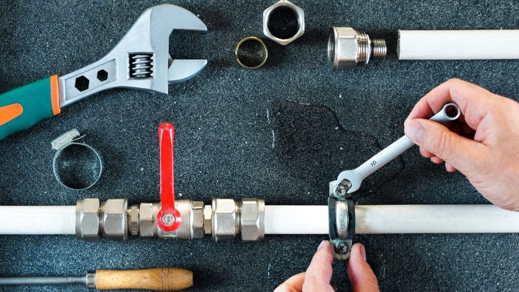 Plumber repairing a pipe valve with an adjustable wrench in Powder Springs