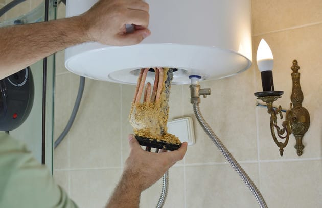 Technician removing mineral buildup from a water heater in Powder Springs