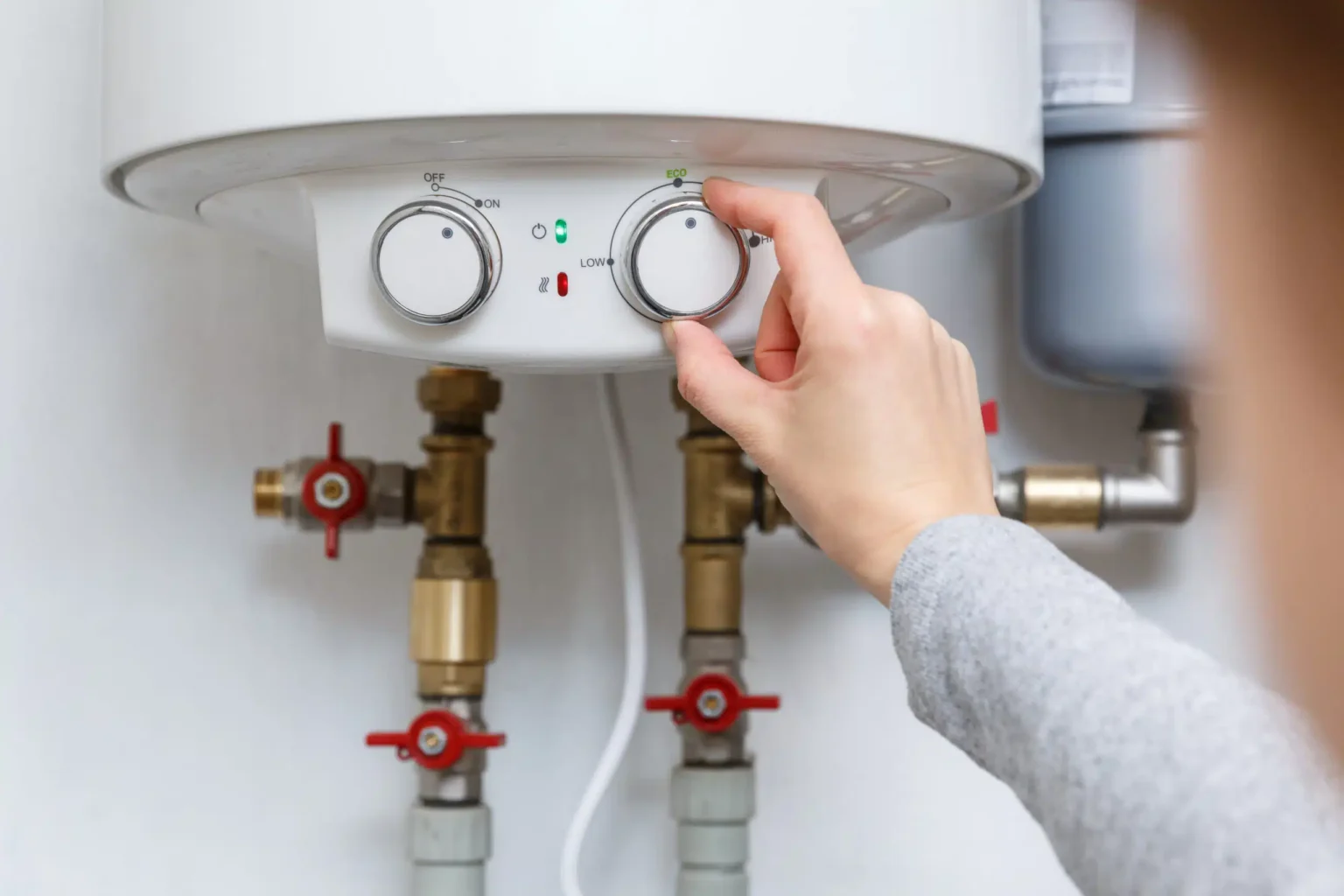 Homeowner adjusting the temperature controls on a water heater in Powder Springs